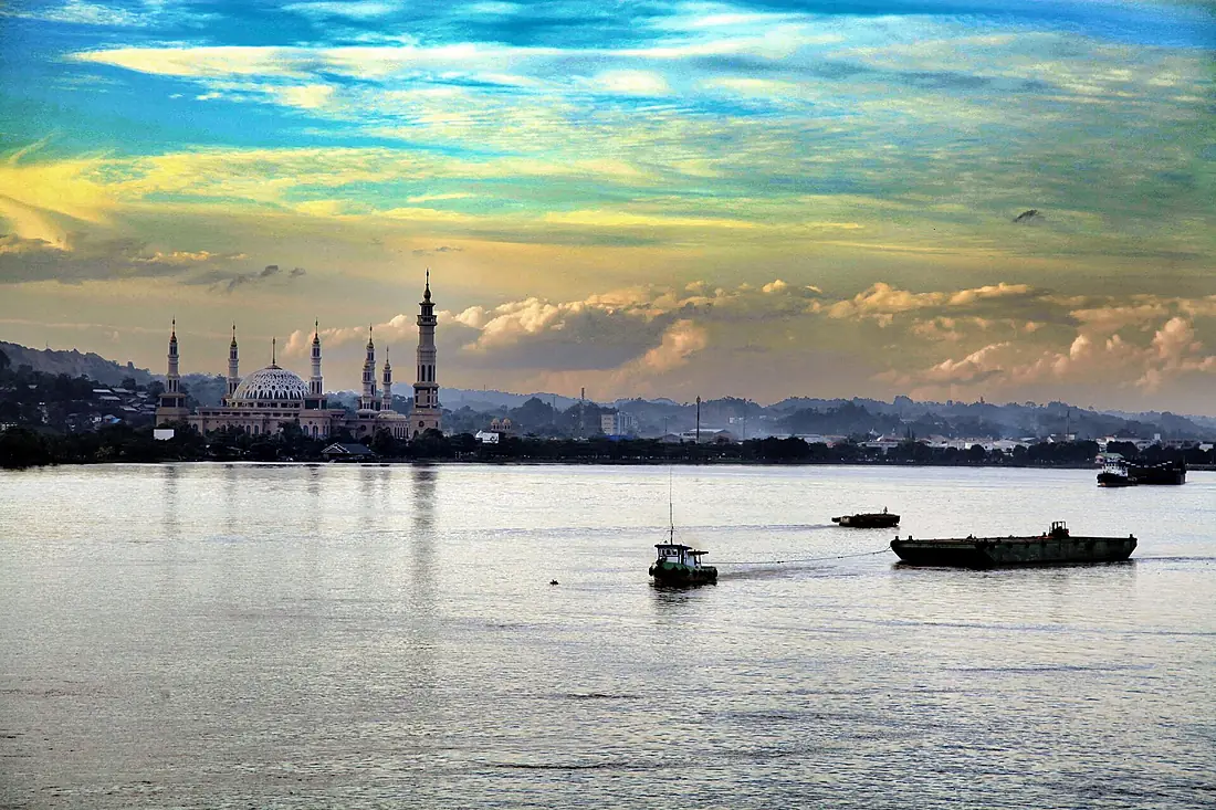 Aktivitas di Sungai Mahakam, Kalimantan Timur, dengan masjid di latar belakang